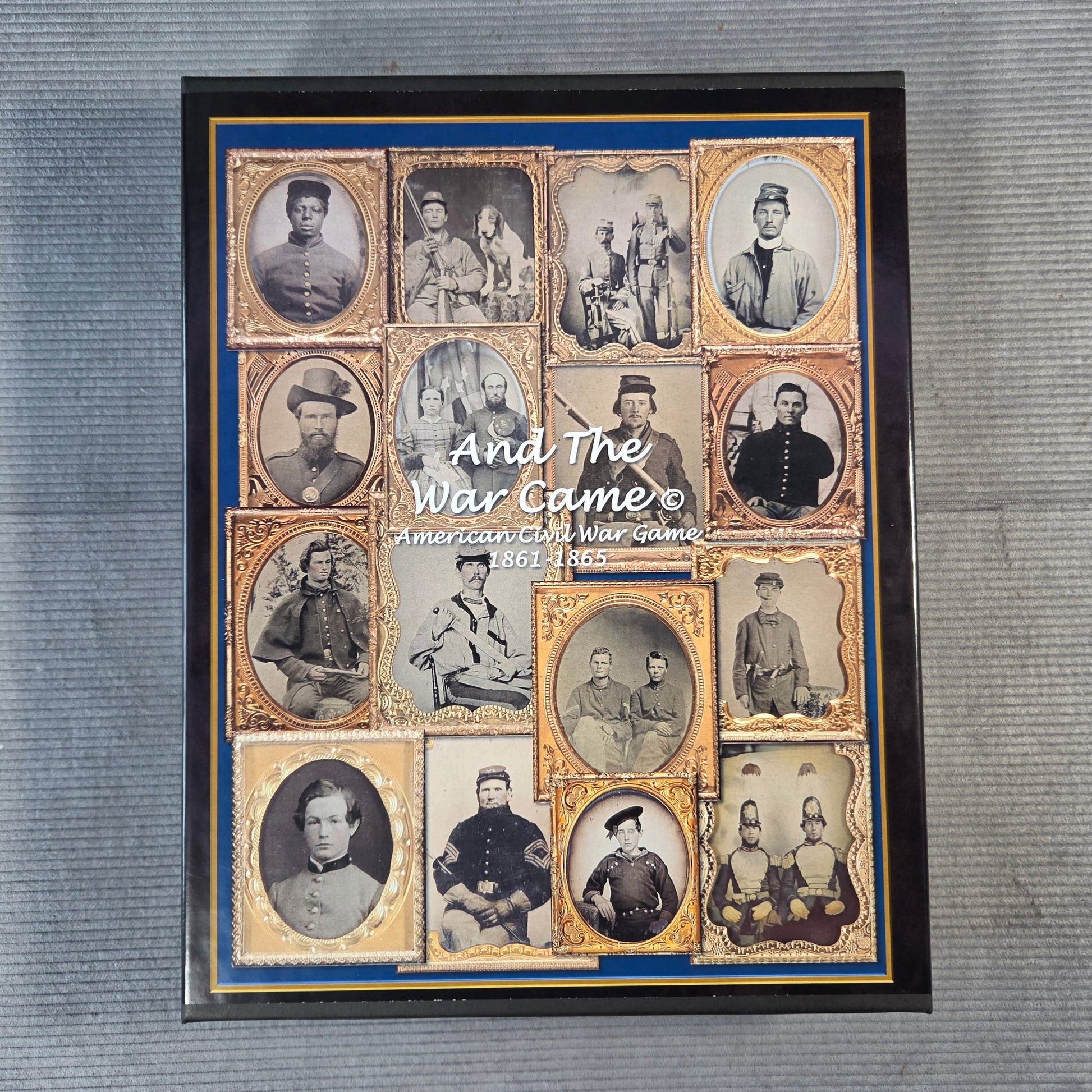 A framed historical collage print titled 'And The War Came' showing multiple vintage portrait photographs arranged in a grid with gold borders and a blue inner border, placed on a gray textured surface.
