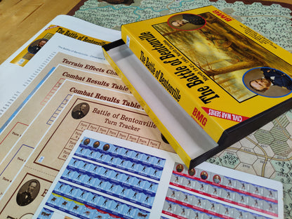 War tabletop game with rules book, cards, and map on a wooden surface.