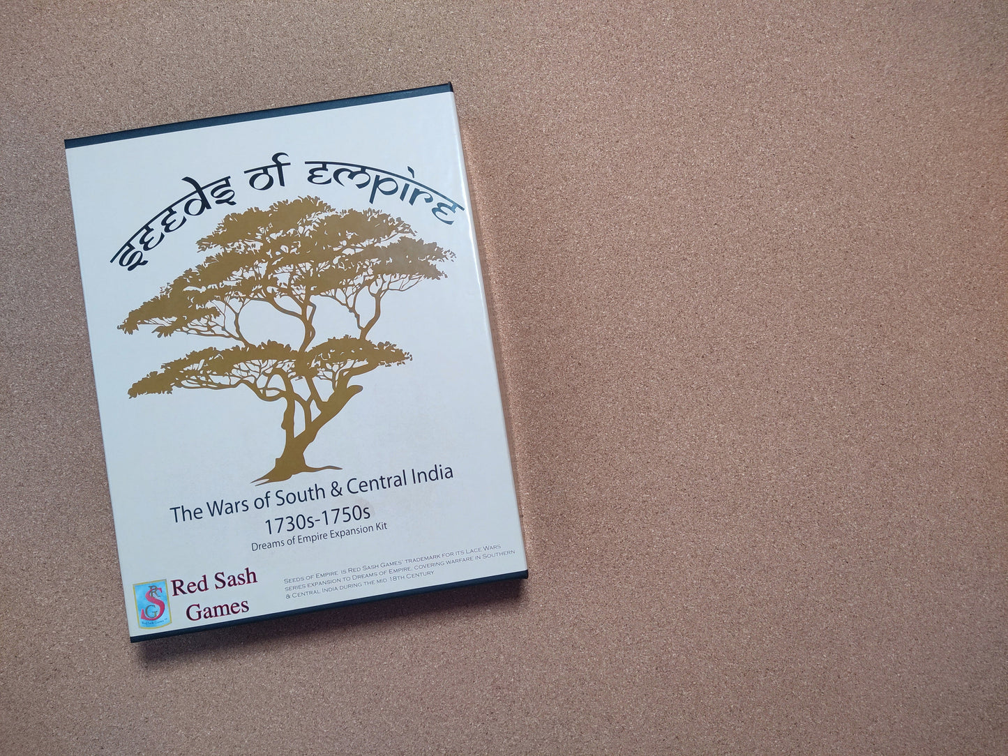 Board game box titled 'Seeds of Empire' by Red Sash Games on a brown surface.