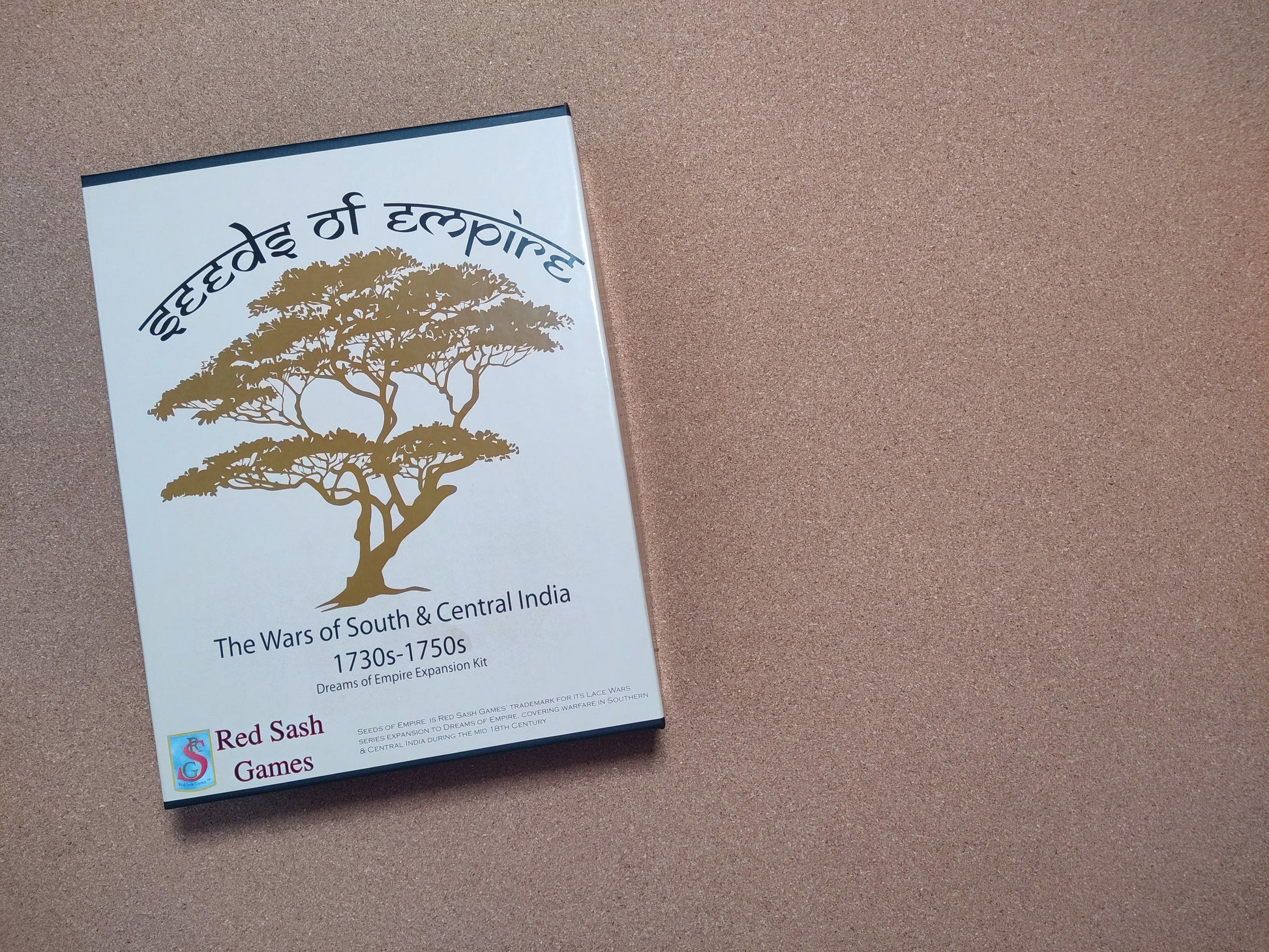 Board game box titled 'Seeds of Empire' by Red Sash Games on a brown surface.