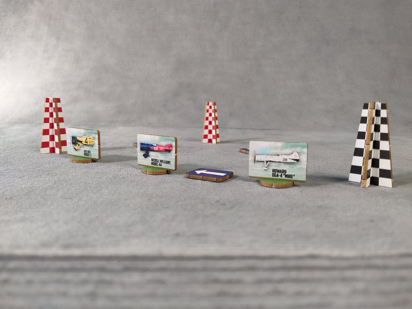 Model race track with planes and checkered flags on a gray surface.