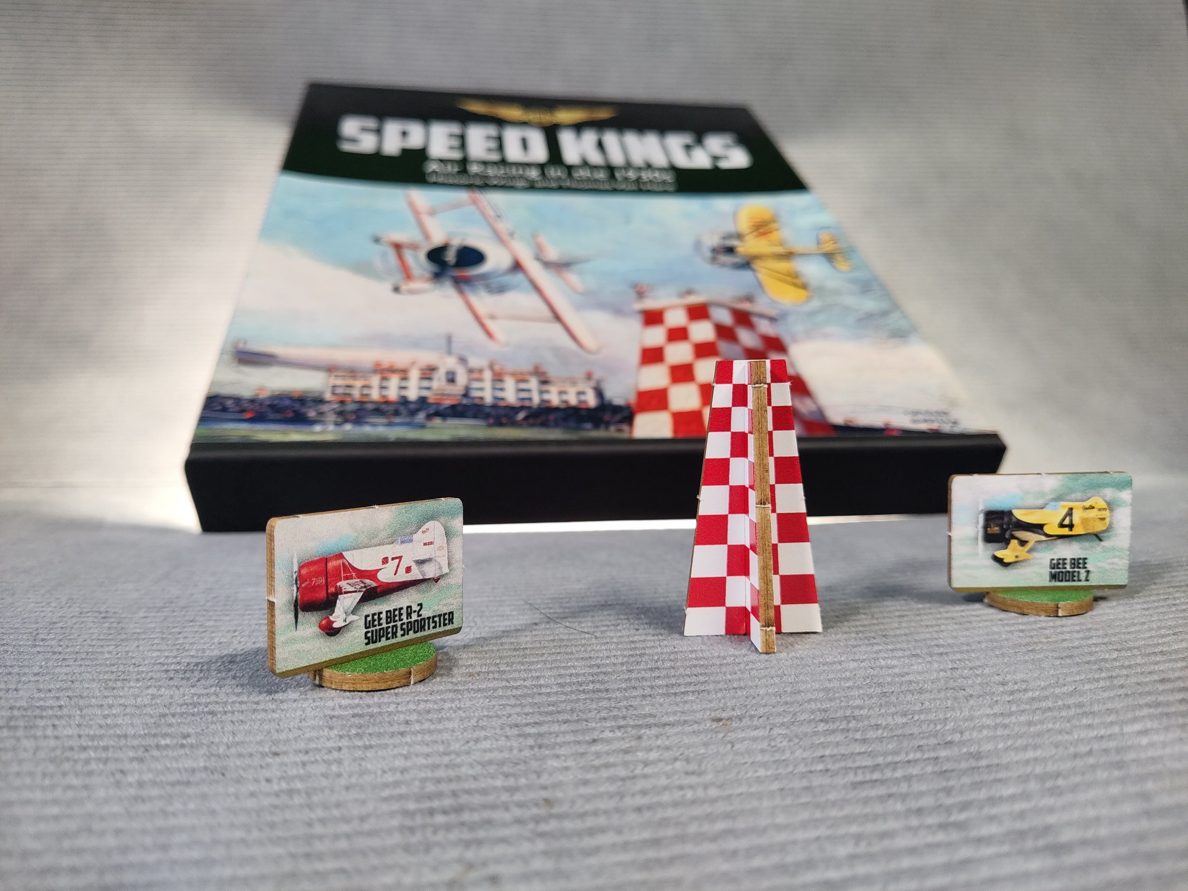 Model racing planes with a 'Speed Kings' game box in the background on a gray surface.